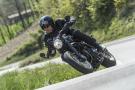 A black Ducati Scrambler Café Racer 2017 being ridden on a rural road